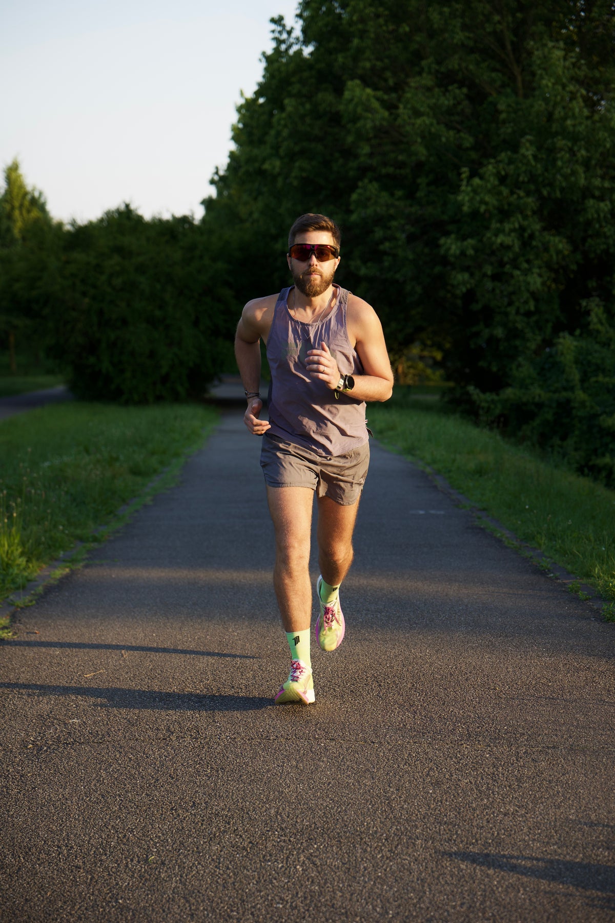 UGC photo — A man running on a paved path. The main focus is on his bright neon green and pink athletic running